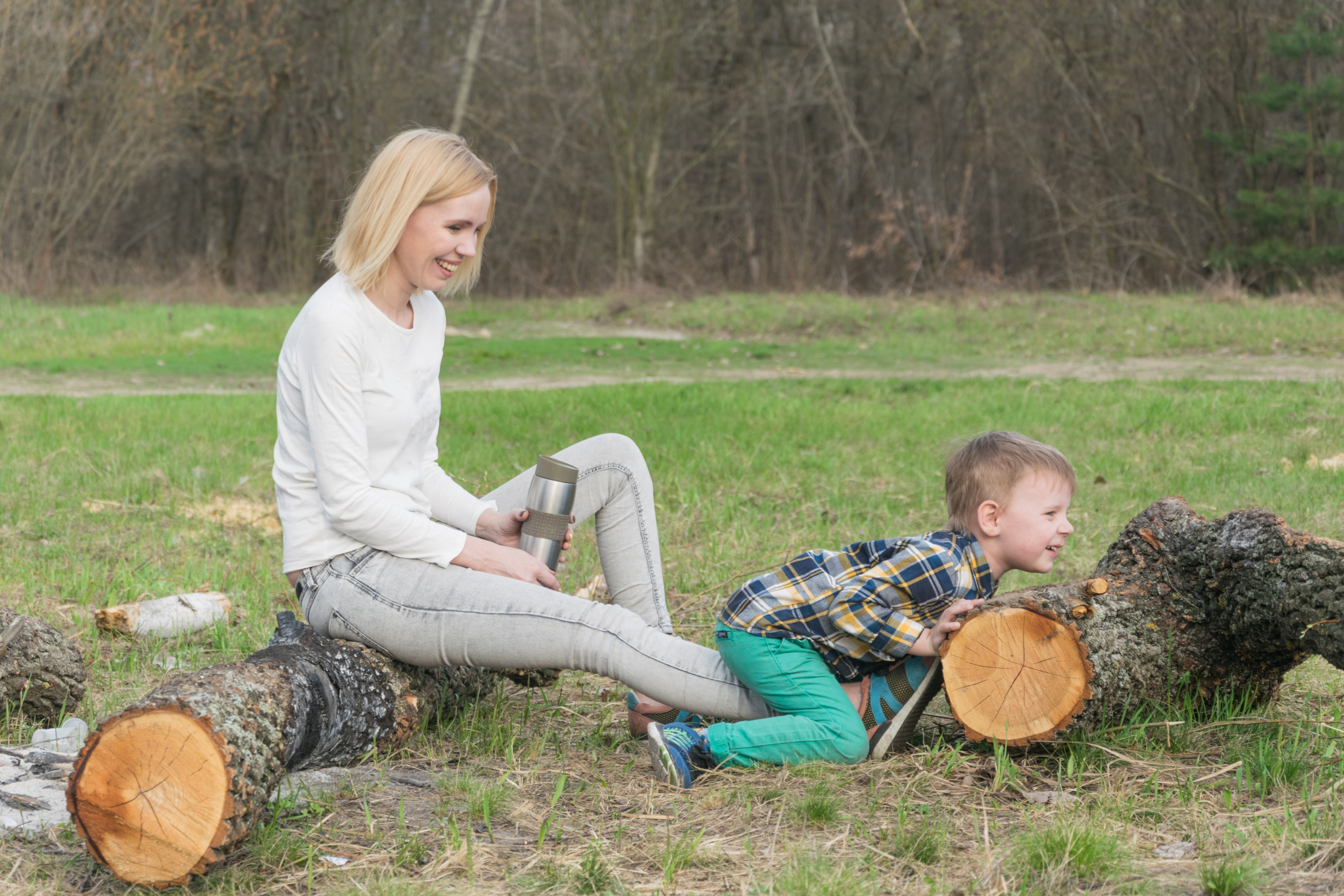 mother watches son push large log